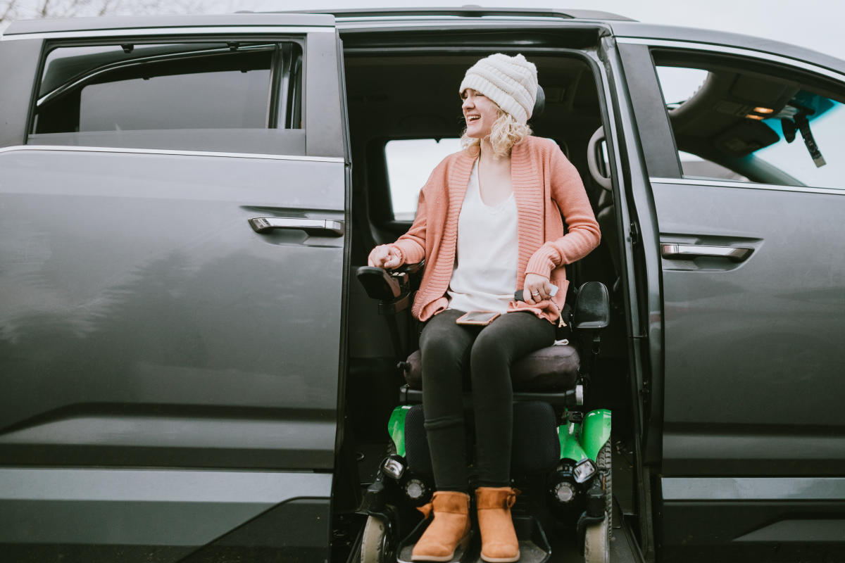 A young woman rides her wheelchair up a ramp in her specially equipped van