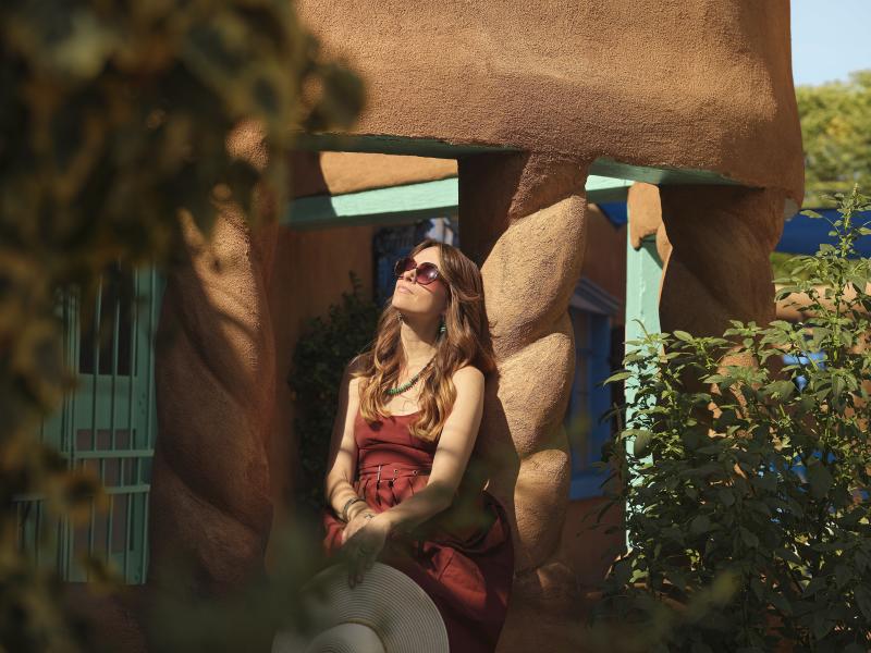 A woman sits on an adobe building in Old Town