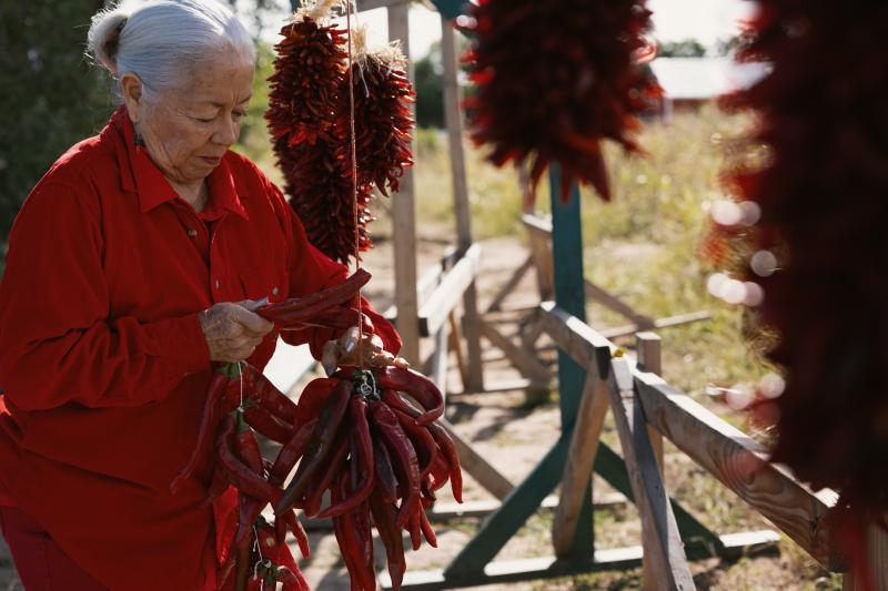 A woman assembles a red chile ristra at Big Jim Farms