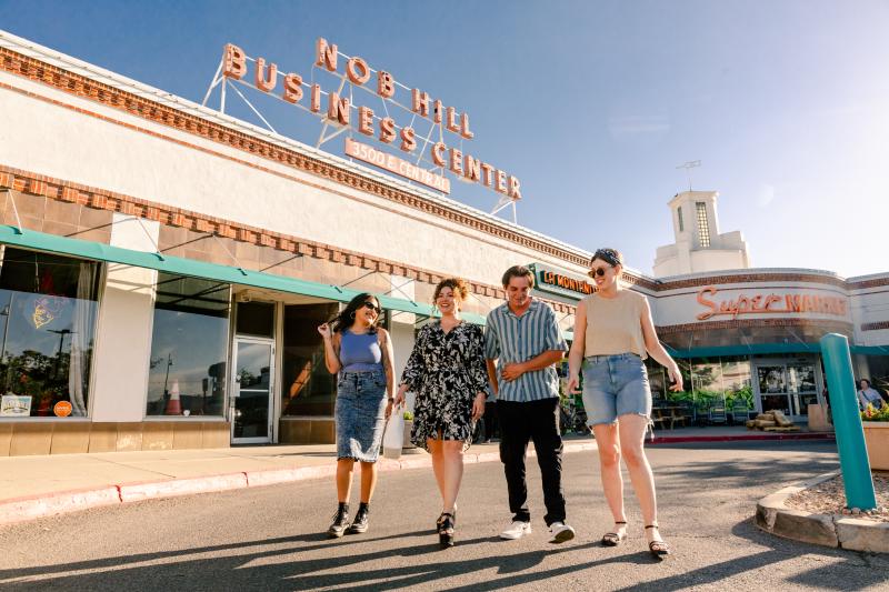 Four people walk in the parking lot of the Nob Hill Business Center.